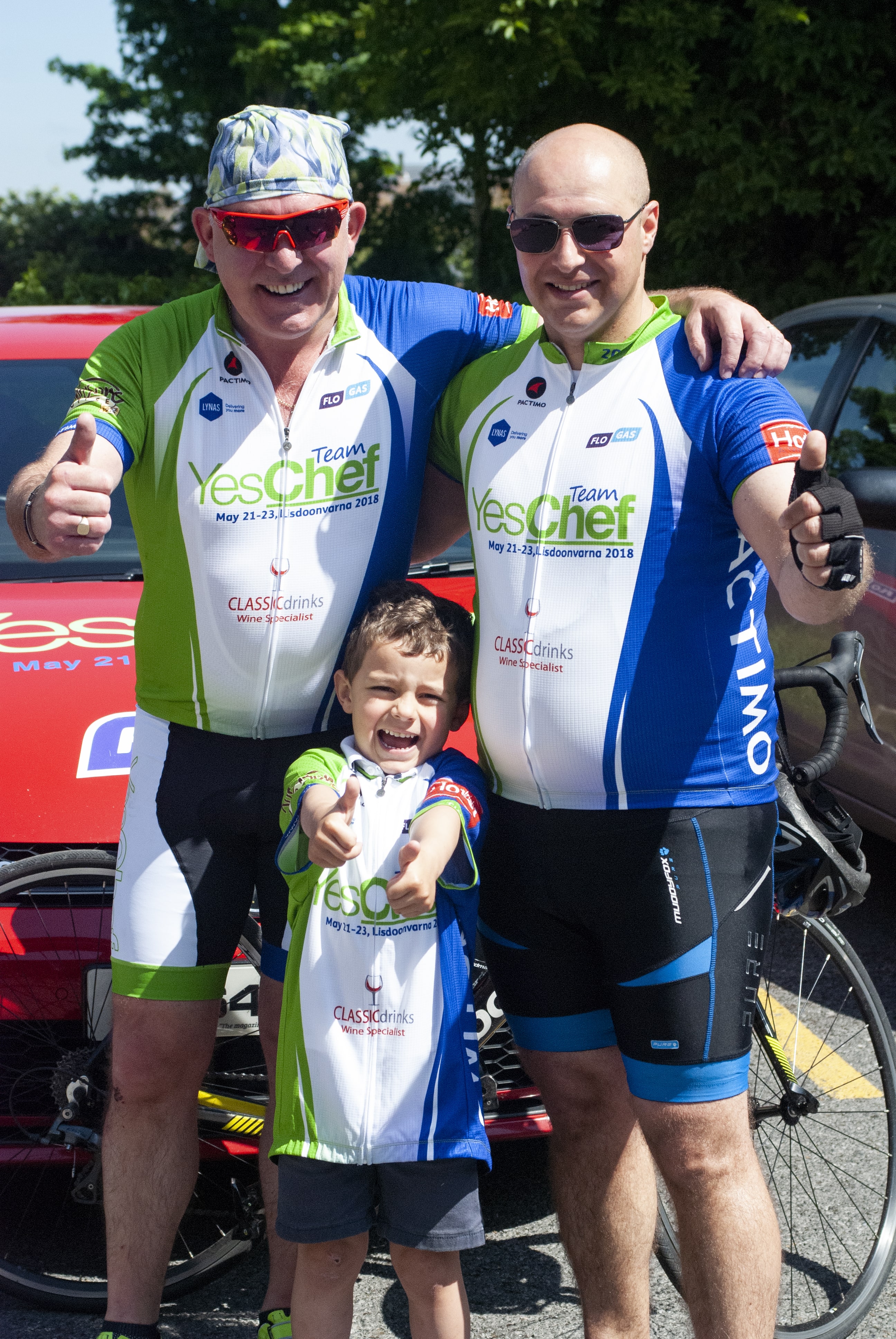 Two men and a child in front of a bike